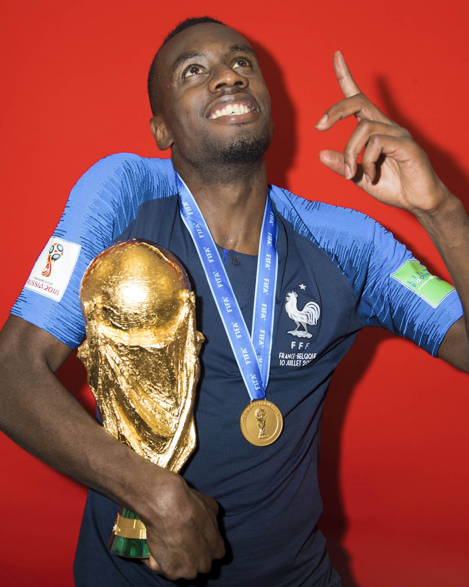 Blaise Matuidi wearing a world cup medal and holding the world cup in his arms